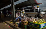 A woman and her daughter wearing face masks to protect against coronavirus sell fruit and vegetables at the taxi station in Lenasia, south of Johannesburg, South Africa, April 8, 2020. (AP Photo/Themba Hadebe)