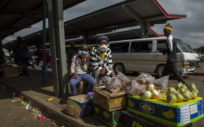 A woman and her daughter wearing face masks to protect against coronavirus sell fruit and vegetables at the taxi station in Lenasia, south of Johannesburg, South Africa, April 8, 2020. (AP Photo/Themba Hadebe)