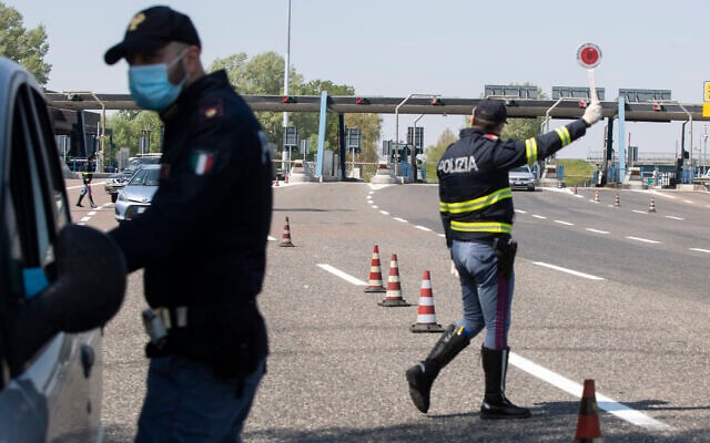 Police officers stop cars at the Melegnano highway barrier entrance, near Milan, Italy, Saturday, April 11, 2020. (AP Photo/Luca Bruno) Police officers stop cars at the Melegnano highway barrier entrance, near Milan, Italy, Saturday, April 11, 2020. (AP Photo/Luca Bruno)