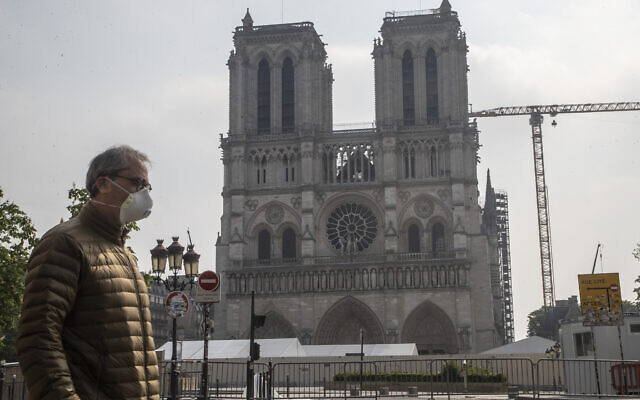 A man wears a mask to protect against the spread of the coronavirus as he walks past the Notre Dame cathedral in Paris, Monday, April 13, 2020. The reconstruction of the fire-devastated Notre Dame Cathedral a year ago on April 15, 2019, was suspended last month due to the coronavirus pandemic. (AP Photo/Michel Euler) A man wears a mask to protect against the spread of the coronavirus as he walks past the Notre Dame cathedral in Paris, Monday, April 13, 2020. The reconstruction of the fire-devastated Notre Dame Cathedral a year ago on April 15, 2019, was suspended last month due to the coronavirus pandemic. (AP Photo/Michel Euler)