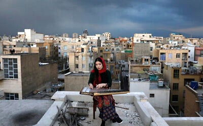 In this March 26, 2020, photo, Mojgan Hosseini, a 28-year-old member of the National Orchestra of Iran, plays Qanun on the roof of her home during mandatory self-isolation due to the new coronavirus disease outbreak, in Tehran, Iran. (AP Photo/Ebrahim Noroozi)