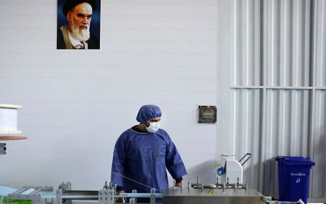 Under a portrait of the late Iranian revolutionary founder Ayatollah Khomeini, a worker wearing a protective suit controls a machine which makes face masks at a factory in Eshtehard, some 70 miles west of the capital Tehran, Iran, Tuesday, April 14, 2020 (AP Photo/Vahid Salemi) Under a portrait of the late Iranian revolutionary founder Ayatollah Khomeini, a worker wearing a protective suit controls a machine which makes face masks at a factory in Eshtehard, some 70 miles west of the capital Tehran, Iran, Tuesday, April 14, 2020 (AP Photo/Vahid Salemi)