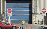 A worker wears a mask as he cleans up an area outside an entrance to Boeing Coroporation's airplane assembly facility north of Seattle, April 13, 2020. (AP Photo/Ted S. Warren, File)