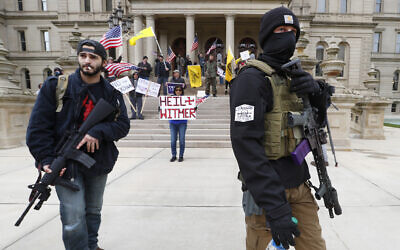 Protesters carry rifles near the steps of the Michigan State Capitol building in Lansing, Michigan, April 15, 2020. (AP Photo/Paul Sancya)
