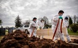 US gravediggers carry the casket of someone presumed to have died from coronavirus as they are buried without any family present at Mount Richmond Cemetery in the Staten Island borough of New York, April 7, 2020. (AP Photo/David Goldman)