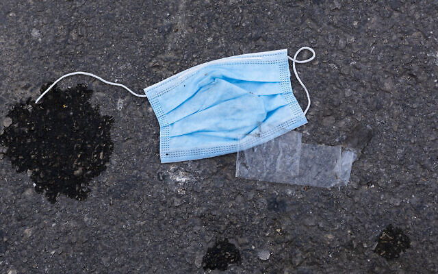 In this April 4, 2020, photo, a protective face mask is thrown on the ground outside a supermarket during a lockdown following government measures to help stop the spread of the coronavirus in Tel Aviv, Israel. (AP Photo/Oded Balilty)