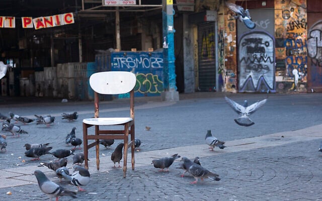 In this March 25, 2020, photo, a "don't panic" sign hangs on the entrance of a food market that was shut down in order to reduce the spread of the coronavirus, in Tel Aviv, Israel. (AP Photo/Oded Balilty)