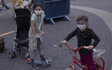 Children wear protective face masks in Tel Aviv, March 24, 2020. (AP Photo/Oded Balilty)