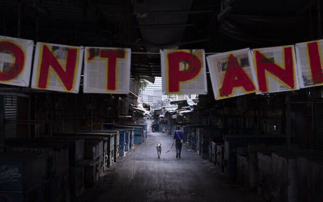 In this March 24, 2020 photo, a "Don't panic" sign hangs on the entrance of a food market that was shut down in order to reduce the spread of the coronavirus, in Tel Aviv, Israel. (AP Photo/Oded Balilty)