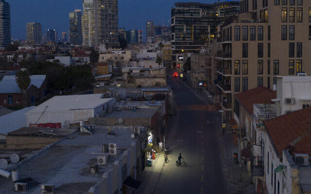 In this March 25, 2020, photo, a man rides a bicycle on an empty road during lockdown following government measures to help stop the spread of the coronavirus in Tel Aviv, Israel. (AP Photo/Oded Balilty)