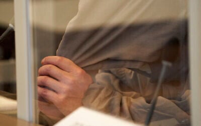 One of the defendants, Eyad A., is sitting on the bench of the Higher Regional Court behind Corona protective screens, hiding his face under a hood in Koblenz, Germany, on April 23, 2020. (Thomas Frey/dpa via AP)