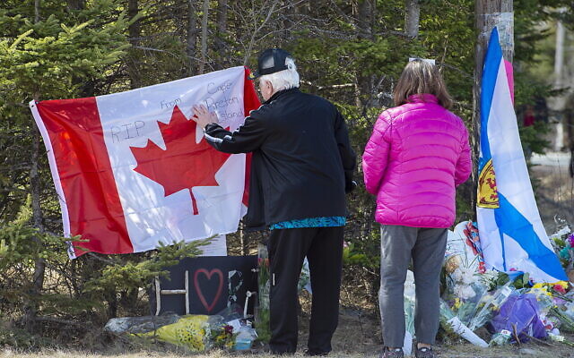 In this photo from April 22, 2020, a couple place a flag at a memorial in Portapique, Nova Scotia, following a deadly shooting rampage. (Andrew Vaughan/The Canadian Press via AP) In this photo from April 22, 2020, a couple place a flag at a memorial in Portapique, Nova Scotia, following a deadly shooting rampage. (Andrew Vaughan/The Canadian Press via AP)