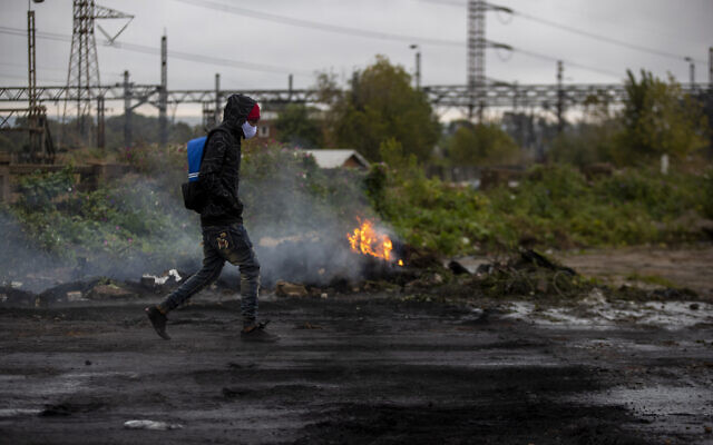 A man wearing a face mask to protect against the coronavirus, walks past burning tyres after a protest over food parcels erupted in Johannesburg, South Africa, Tuesday, April 28, 2020. Many have lost their income as South Africa is under a strict five-week lockdown in a effort to fight the coronavirus pandemic. (AP Photo/Themba Hadebe) A man wearing a face mask to protect against the coronavirus, walks past burning tyres after a protest over food parcels erupted in Johannesburg, South Africa, Tuesday, April 28, 2020. Many have lost their income as South Africa is under a strict five-week lockdown in a effort to fight the coronavirus pandemic. (AP Photo/Themba Hadebe)