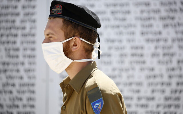 An Israeli soldier wearing a protective face mask amid concerns over the country's coronavirus outbreak stands in honor, in front of names of fallen soldiers at the Armored Corps Memorial during the country's memorial day for fallen soldiers and victims of attacks, in Latrun, Israel, Tuesday, April 28, 2020. The somber day of mourning comes as Israel is beginning to relax stringent measures meant to combat the country's coronavirus outbreak. But with the memorial day and then Israeli Independence Day beginning Tuesday evening, Israel temporarily tightened restrictions meant to prevent gatherings and crowds that could set off new infections. (AP Photo/Ariel Schalit) An Israeli soldier wearing a protective face mask amid concerns over the country's coronavirus outbreak stands in honor, in front of names of fallen soldiers at the Armored Corps Memorial during the country's memorial day for fallen soldiers and victims of attacks, in Latrun, Israel, Tuesday, April 28, 2020. The somber day of mourning comes as Israel is beginning to relax stringent measures meant to combat the country's coronavirus outbreak. But with the memorial day and then Israeli Independence Day beginning Tuesday evening, Israel temporarily tightened restrictions meant to prevent gatherings and crowds that could set off new infections. (AP Photo/Ariel Schalit)