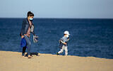 A woman and her son wear face masks as they walk on a beach in Badalona, near Barcelona, Spain, April 28, 2020 as the lockdown to combat the spread of coronavirus continues. (AP Photo/Emilio Morenatti)