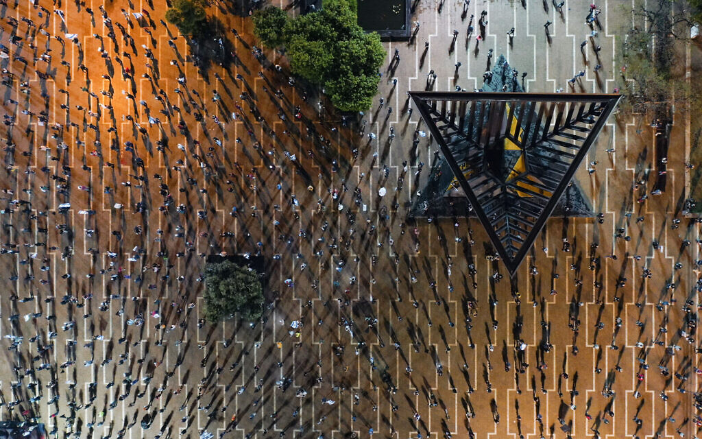 In this Saturday, April 25, 2020 photo, people keep social distancing amid concerns over the country's coronavirus outbreak, during "Black Flag" protest against Prime Minister Benjamin Netanyahu and government corruption, at Rabin Square in Tel Aviv, Israel. (AP Photo/Oded Balilty)