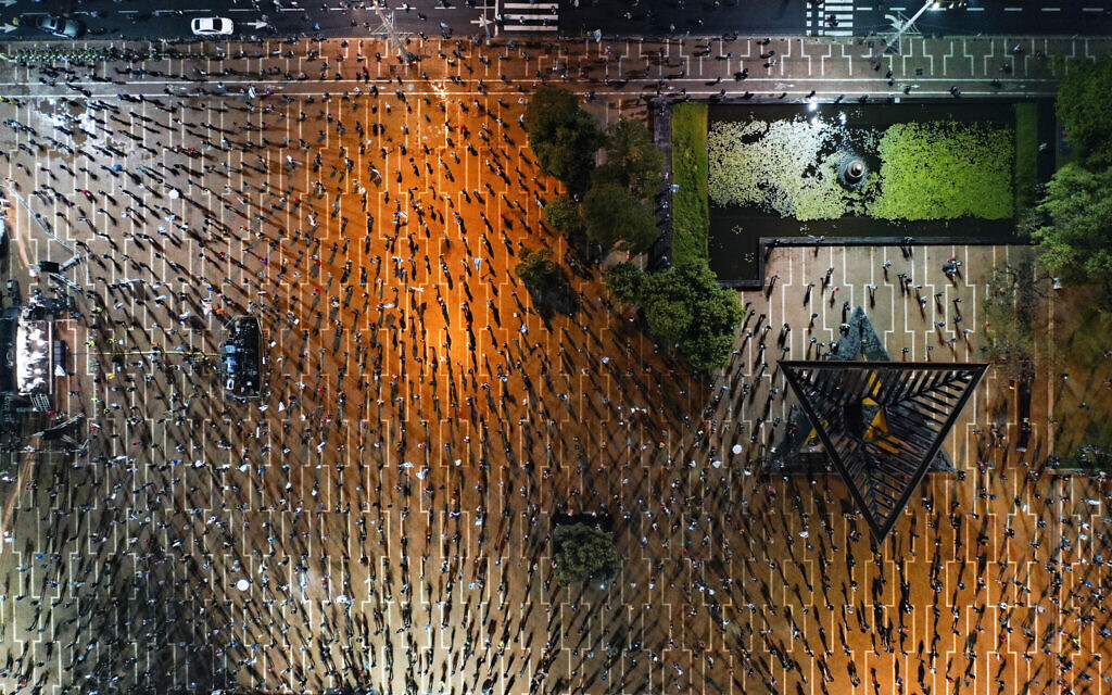 In this April 25, 2020 photo, people keep social distancing amid concerns over the country's coronavirus outbreak, during a 'Black Flag' protest against Prime Minister Benjamin Netanyahu and government corruption, at Rabin Square in Tel Aviv. (AP Photo/Oded Balilty)