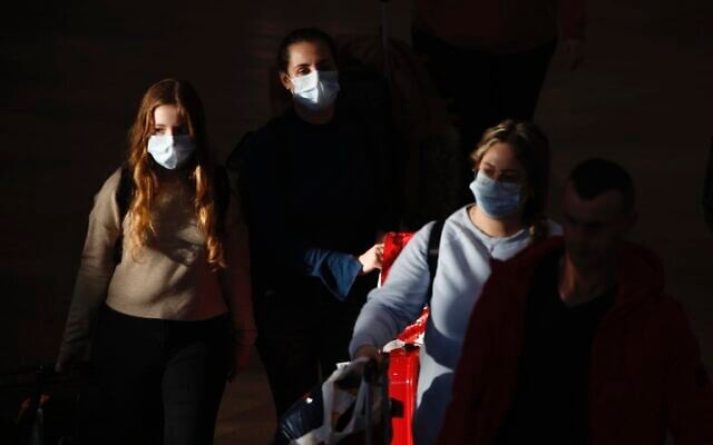 Illustrative: Travelers wearing protective masks arrive at Ben Gurion Airport, Feb. 27, 2020. (AP Photo/Ariel Schalit) Illustrative: Travelers wearing protective masks arrive at Ben Gurion Airport, Feb. 27, 2020. (AP Photo/Ariel Schalit)