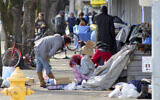 In this March 3, 2020, photo, homeless people crowd a sidewalk in downtown Salem, Oregon, where they have set up a makeshift camp. (AP Photo/Andrew Selsky)