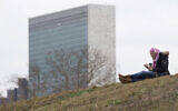 A woman listens to music at a park on Roosevelt Island, Tuesday, March 17, 2020, in New York, with a United Nations building in the background. (AP/Mary Altaffer)