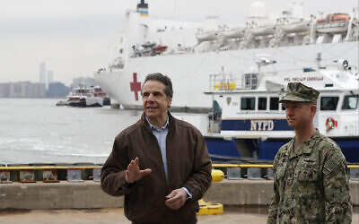 New York Gov. Andrew Cuomo, left, gestures during a brief news conference as he stands beside a Rear Adm. John B. Mustin as the USNS Comfort, a naval hospital ship with a 1,000 bed-capacity, pulls into Pier 90 Monday, March 30, 2020, in New York. (AP Photo/Kathy Willens)