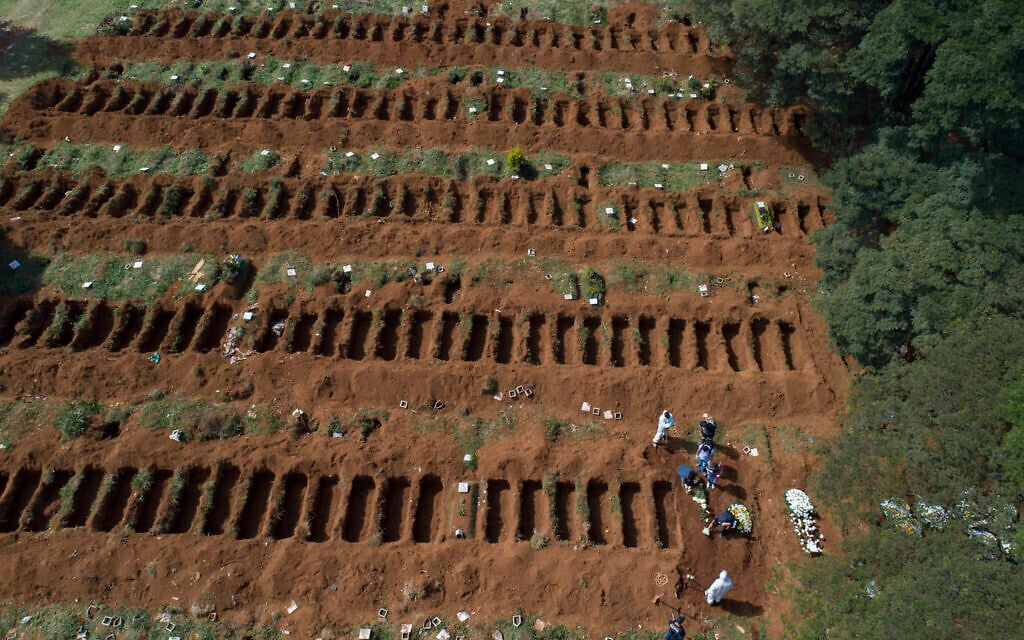 Cemetery workers in protective clothing bury a person at the Vila Formosa cemetery in Sao Paulo, Brazil, Wednesday, April 1, 2020. Vila Formosa cemetery, the largest in Latin America, has had a 30 percent increase in the number of burials amid spread of the new coronavirus, according to the cemetery's administration. (AP Photo/Andre Penner)