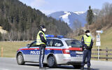 Police officers block the road to the skiing resort Saalbach Hinterglemm in  Austrian province of Salzburg, Friday, April 3, 2020 after the city was quarantined. (AP Photo/Kerstin Joensson)