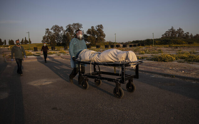 A member of Hevra Kadisha, an organization which prepares bodies of deceased Jews for burial according to Jewish tradition, pushes a body during a funeral of a Jewish man who died from coronavirus in the costal city of Ashkelon, Israel, April 2, 2020. (AP Photo/Tsafrir Abayov) A member of Hevra Kadisha, an organization which prepares bodies of deceased Jews for burial according to Jewish tradition, pushes a body during a funeral of a Jewish man who died from coronavirus in the costal city of Ashkelon, Israel, April 2, 2020. (AP Photo/Tsafrir Abayov)