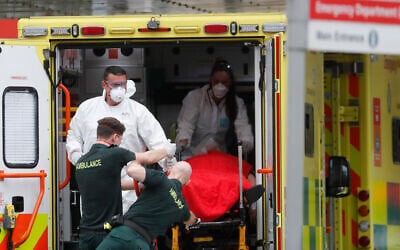 Medical workers wearing equipment to protect themselves from coronavirus bring a patient to St Thomas' Hospital in Westminster in London, April 6, 2020 (AP Photo/Frank Augstein)