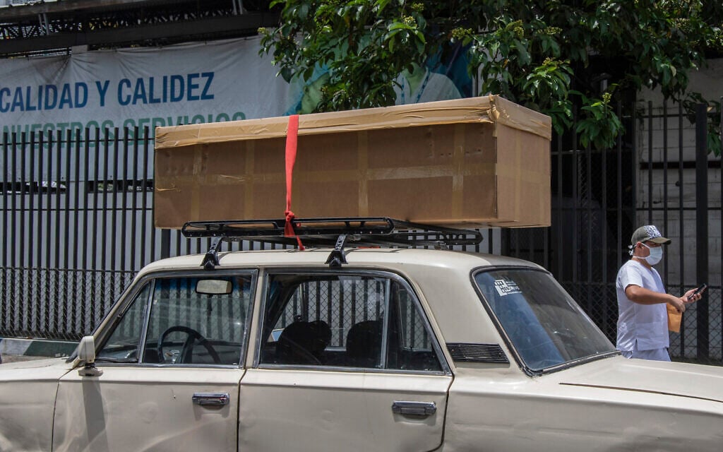 A cardboard coffin with a body sits on the roof rack of a car before it is taken away to be buried, outside the Teodoro Maldonado Hospital in Guayaquil, Ecuador, Monday, April 6, 2020. (AP Photo/Luis Perez)