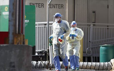 Medical personnel carry an oxygen tank into Elmhurst Hospital Center's emergency room after inspecting it outdoors, April 7, 2020, in New York during the current coronavirus outbreak. (AP Photo/Kathy Willens)