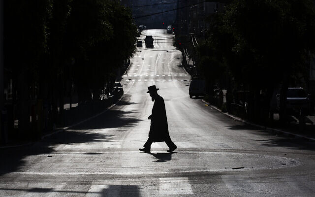 An ultra-Orthodox Jew crosses a mainly deserted street because of the government's measures to help stop the spread of the coronavirus, in Bnei Brak, Israel, Wednesday, April 8, 2020. (AP Photo/Oded Balilty) An ultra-Orthodox Jew crosses a mainly deserted street because of the government's measures to help stop the spread of the coronavirus, in Bnei Brak, Israel, Wednesday, April 8, 2020. (AP Photo/Oded Balilty)