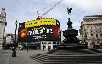 A video screen displays a message urging people to stay home in a nearly deserted Piccadilly Circus in London, Wednesday, April 8, 2020. (AP Photo/Matt Dunham)