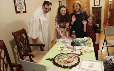 Rabbi Shlomo Segal, left, and his family wave goodbye to participants after he conducted a virtual Passover seder for members of his congregation, friends and family and broadcast it on YouTube and internet dial-in connections from his home in the Sheepshead Bay section of Brooklyn during the current coronavirus outbreak, Wednesday, April 8, 2020, in New York. From left, are Segal, daughter Shira, 12, wife Adina and daughter Rayna, 8. (AP/Kathy Willens)