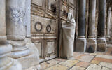 A Christian worshiper stands at the closed door of the Church of the Holy Sepulchre, believed by many Christians to be the site of the crucifixion and burial of Jesus Christ, in Jerusalem, April 10, 2020 (AP Photo/Sebastian Scheiner)