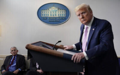 Director of the National Institute of Allergy and Infectious Diseases Dr. Anthony Fauci, left, listens as US President Donald Trump speaks during a coronavirus task force briefing at the White House, in Washington, April 10, 2020. (Evan Vucci/AP)