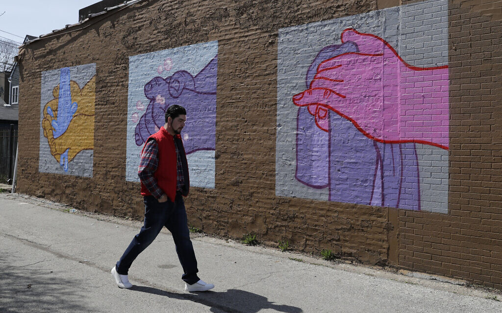 A man walks by a mural depicting hand washing in Logan Square by artist James Mosher, Saturday, April 11, 2020 in Chicago. (AP Photo/Nam Y. Huh) A man walks by a mural depicting hand washing in Logan Square by artist James Mosher, Saturday, April 11, 2020 in Chicago. (AP Photo/Nam Y. Huh)