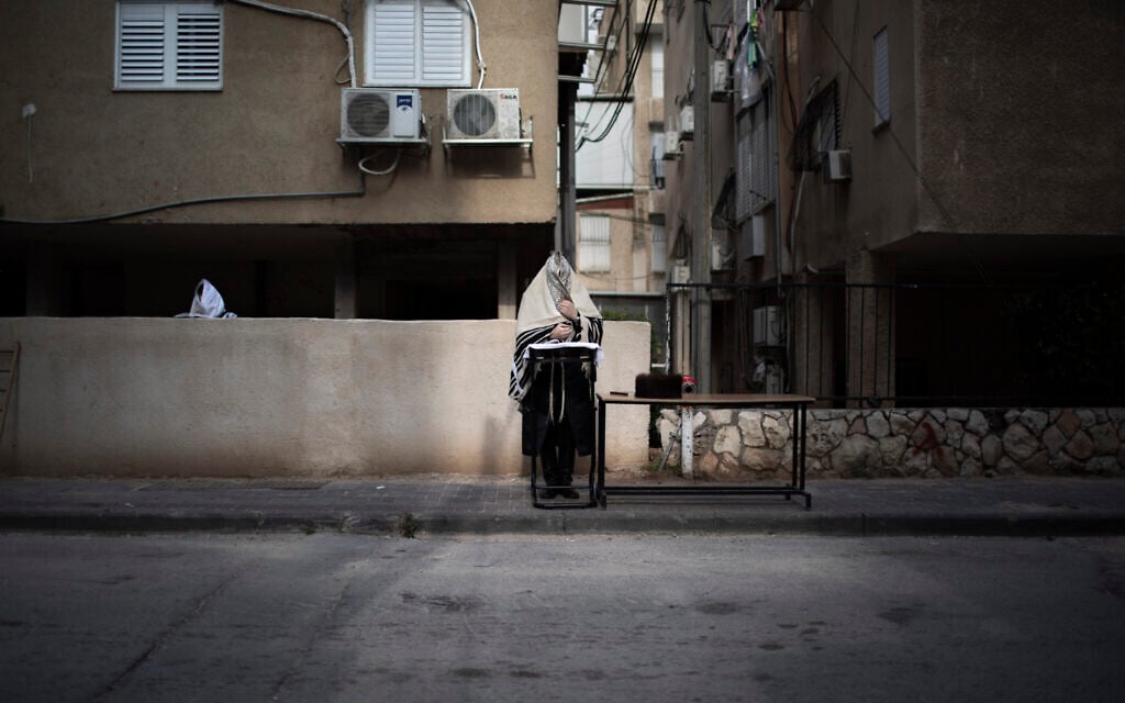 Ultra-Orthodox men pray the morning prayer next to their house as synagogues are closed following the government's measures to help stop the spread of the coronavirus, in Bnei Brak,  April 14, 2020. (AP Photo/Oded Balilty)