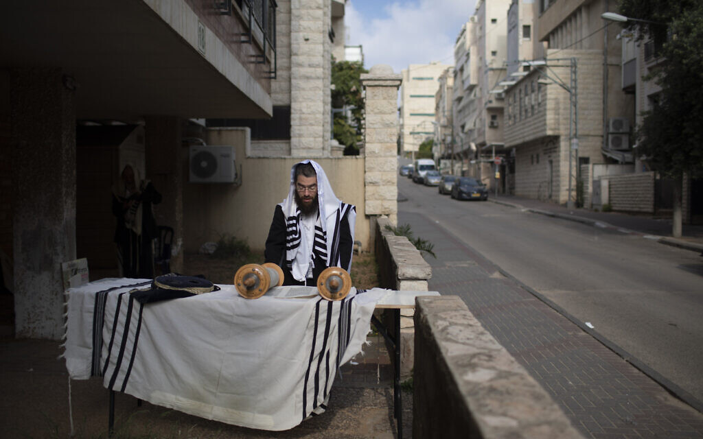 An ultra-Orthodox Jew prays next to his house as synagogues are closed following the government's measures to help stop the spread of the coronavirus, in Bnei Brak,  April 14, 2020. (AP Photo/Oded Balilty)