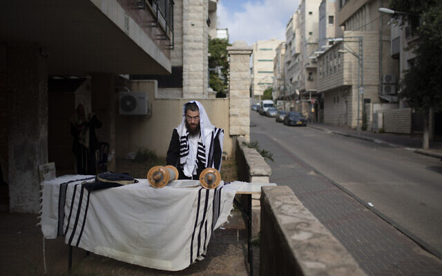 An ultra-Orthodox Jew prays next to his house as synagogues are closed following the government's measures to help stop the spread of the coronavirus, in Bnei Brak,  April 14, 2020. (AP Photo/Oded Balilty)