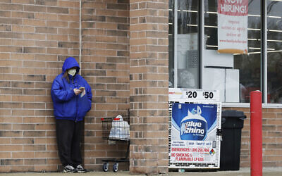 A woman checks her phone as a hiring sign shows at a Family Dollar store in Illinois, April 17, 2020. (AP Photo/Nam Y. Huh)