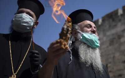 An Orthodox clergyman holds the holy fire to transfer to predominantly Orthodox countries from the Church of the Holy Sepulchre, traditionally believed by many Christians to be the site of the crucifixion and burial of Jesus Christ, in Jerusalem's old city after the traditional Holy Fire ceremony was called off amid the coronavirus, April 18, 2020. (AP Photo/Ariel Schalit)