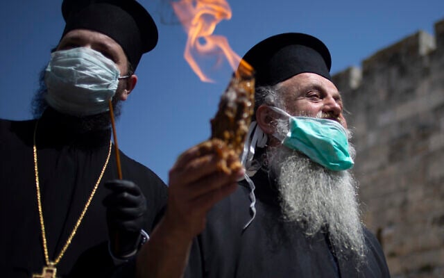 An Orthodox clergyman holds the holy fire to transfer to predominantly Orthodox countries from the Church of the Holy Sepulchre, traditionally believed by many Christians to be the site of the crucifixion and burial of Jesus Christ, in Jerusalem's old city after the traditional Holy Fire ceremony was called off amid the coronavirus, April 18, 2020. (AP Photo/Ariel Schalit)