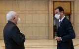 Syrian President Bashar Assad, right, wears a mask to help protect from the coronavirus, as he speaks with Iranian Foreign Minister Mohammad Javad Zarif, who also wore a mask and gloves, in Damascus, Syria, April. 20, 2020. (SANA via AP)