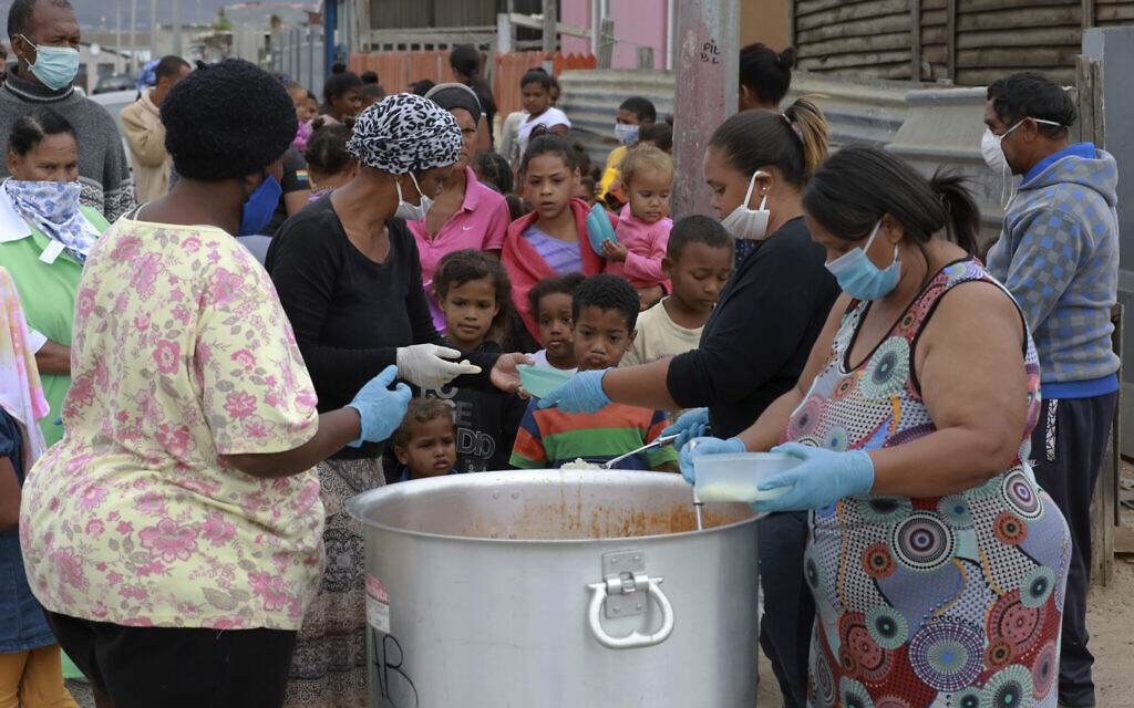Children line up for food at a feeding scheme in Lavender Hill, Cape Town South Africa, Tuesday, April 21, 2020, during the fourth week of lockdown to contain the spread of coronavirus. The feeding of the children has replaced the meal a day they would be fed during their regular school day on a regular basis. (AP Photo/Nardus Engelbrecht)