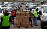 Using part of the Pittsburgh International Airport parking lot that has been left vacant by the COVID-19 pandemic, volunteers from the Greater Pittsburgh Community Food Bank load boxes of food into cars during a drive-up food distribution, on April 22, 2020. (AP Photo/Gene J. Puskar)
