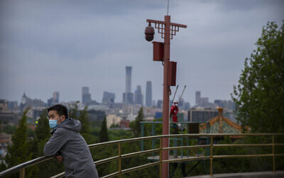 A man wearing a face mask to protect against the spread of the new coronavirus stands on a hilltop at a public park in Beijing, Saturday, April 25, 2020. (AP/Mark Schiefelbein)