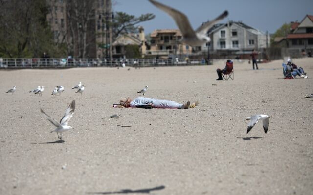 A woman sleeps on Brighton Beach in the Brooklyn borough of New York as seagulls flutter around her, on Saturday, April 25, 2020. (AP/Wong Maye-E) A woman sleeps on Brighton Beach in the Brooklyn borough of New York as seagulls flutter around her, on Saturday, April 25, 2020. (AP/Wong Maye-E)