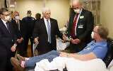 US Vice President Mike Pence, center, visits Dennis Nelson, a patient who survived the coronavirus and was going to give blood, during a tour of the Mayo Clinic Tuesday, April 28, 2020, in Rochester, Minn., as he toured the facilities supporting COVID-19 research and treatment. Pence chose not to wear a face mask while touring the Mayo Clinic in Minnesota. It's an apparent violation of the world-renowned medical center's policy requiring them. (AP Photo/Jim Mone)