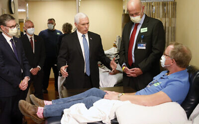 US Vice President Mike Pence, center, visits Dennis Nelson, a patient who survived the coronavirus and was going to give blood, during a tour of the Mayo Clinic Tuesday, April 28, 2020, in Rochester, Minn., as he toured the facilities supporting COVID-19 research and treatment. Pence chose not to wear a face mask while touring the Mayo Clinic in Minnesota. It's an apparent violation of the world-renowned medical center's policy requiring them. (AP Photo/Jim Mone)